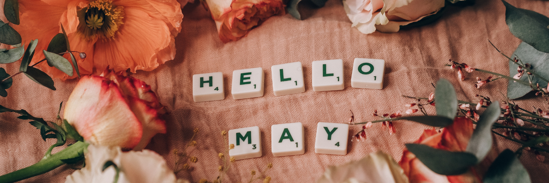 Scrabble tiles spell out Hello May surrounded by flowers